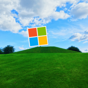 Photo of a vibrant green lawn and hill with a perfect blue sky above. The Microsoft logo sits at the top of the hill.